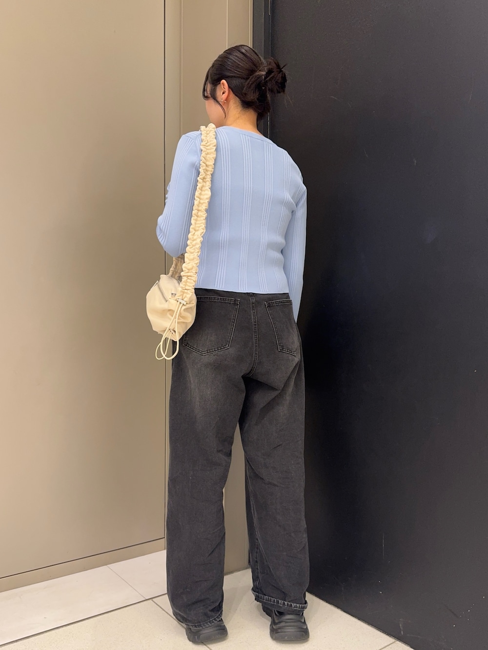 ホワイト系のショルダーバッグ、ブラック系のデニムパンツ、ブラック系のスニーカーを着用したレディースの春コーディネートの3枚目の写真