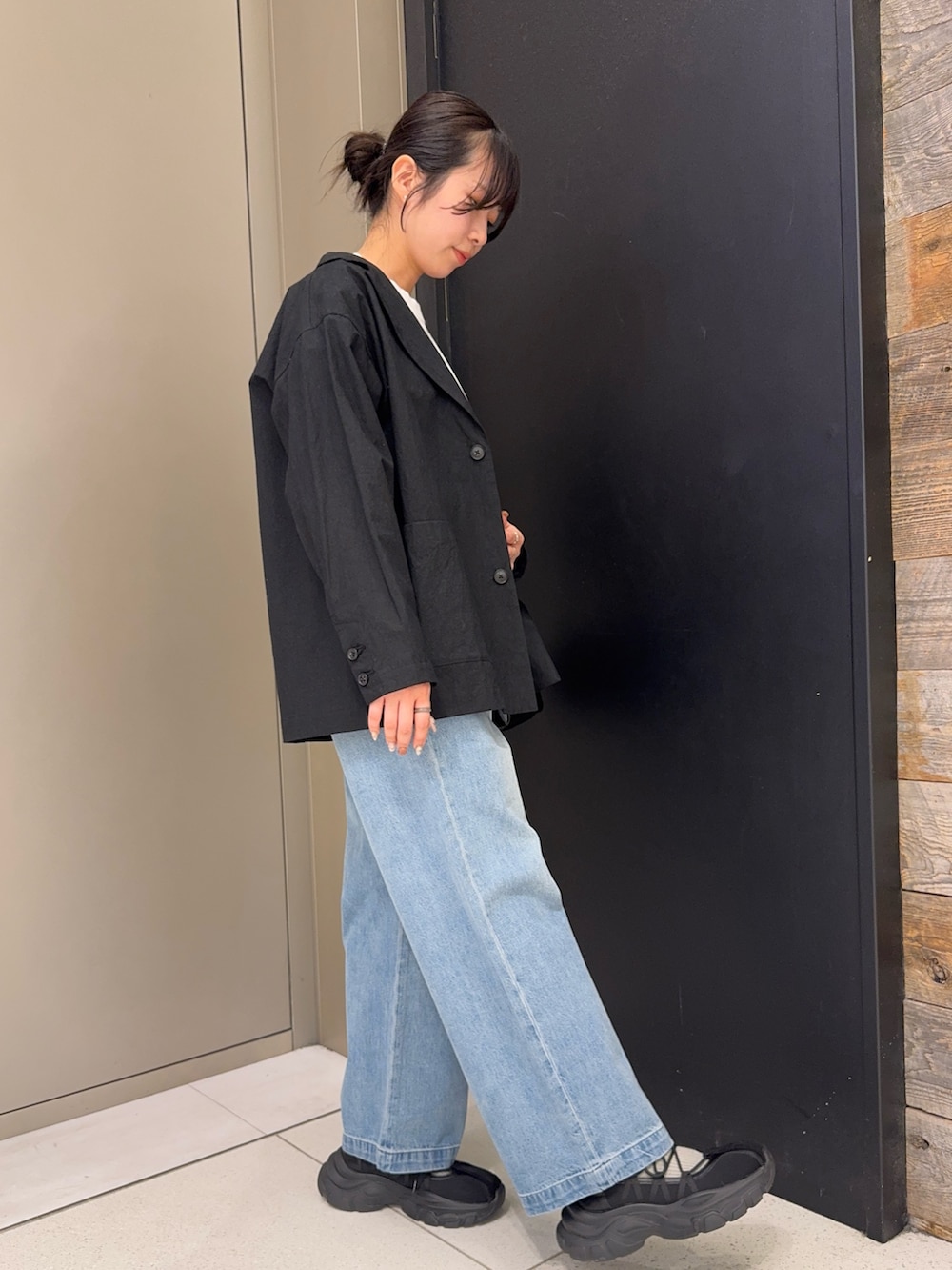 ブラック系のその他アウター、ブラック系のショルダーバッグ、ブルー系のデニムパンツを着用したレディースの春コーディネートの2枚目の写真