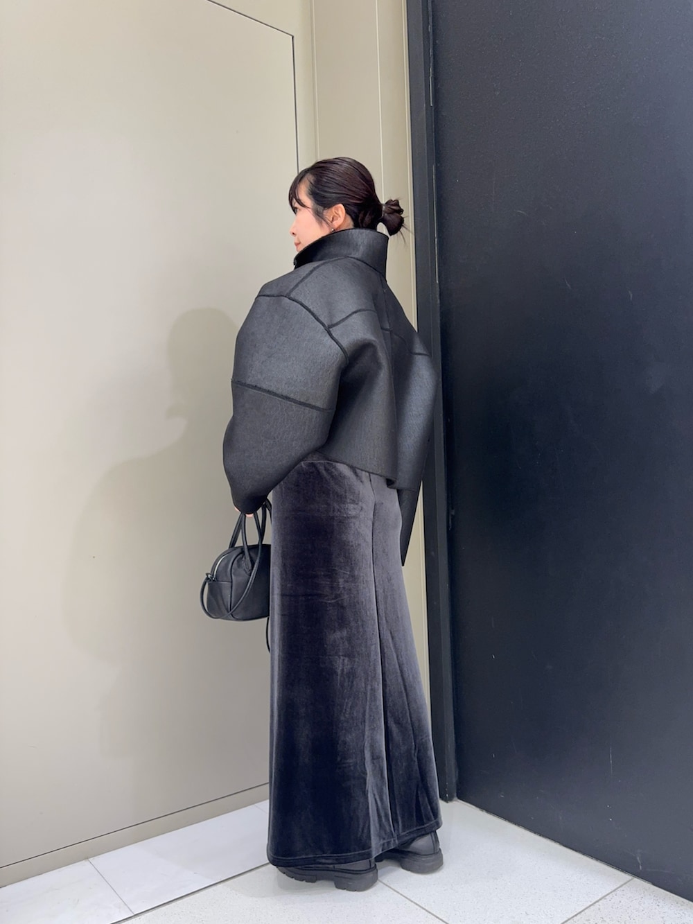 ブラック系のその他アウター、ブラック系のハンドバッグ、グレー系のスカートを着用したレディースの冬コーディネートの2枚目の写真