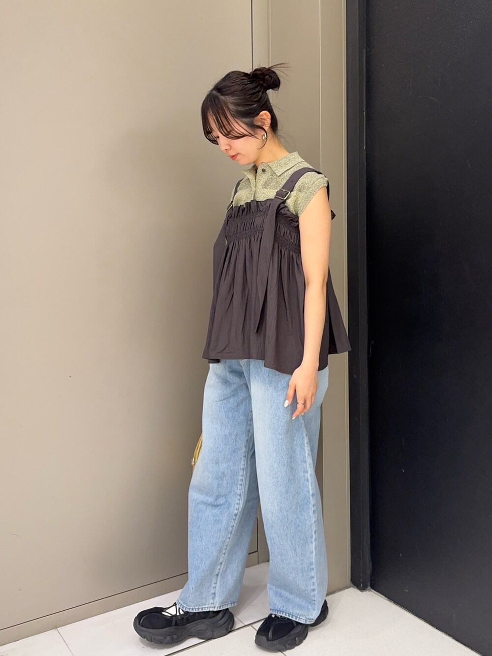 ブルー系のデニムパンツ、ブラック系のスニーカー、ベージュ系のショルダーバッグを着用したレディースの春コーディネートの2枚目の写真