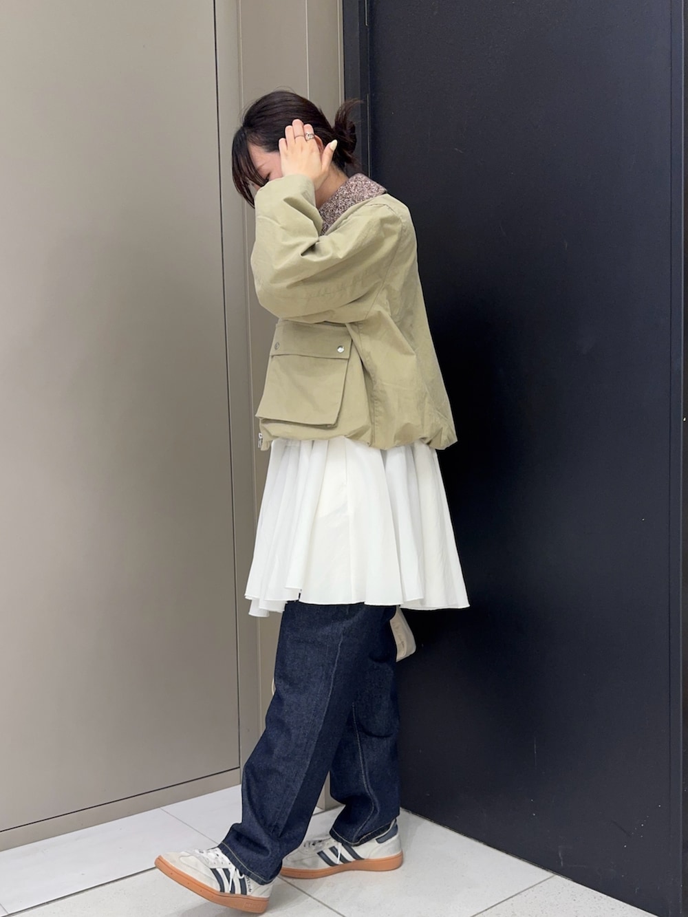 ベージュ系のブルゾン、ホワイト系のワンピース、ブルー系のデニムパンツを着用したレディースの春コーディネートの2枚目の写真