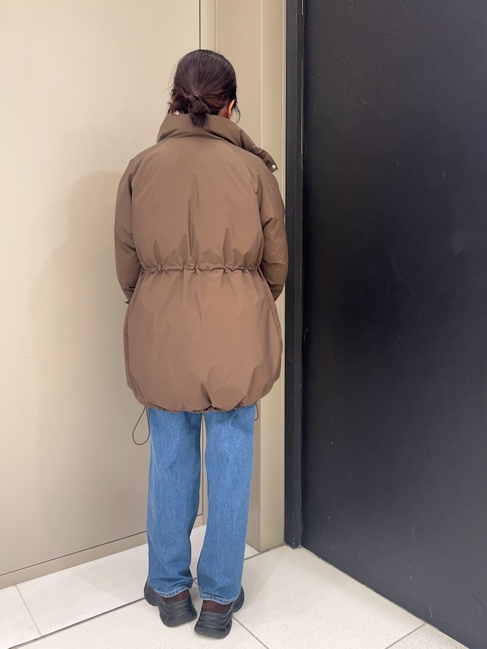 ブラウン系のダウンジャケット/コート、ブルー系のデニムパンツ、ブラウン系のローファーを着用したレディースの冬コーディネートの3枚目の写真