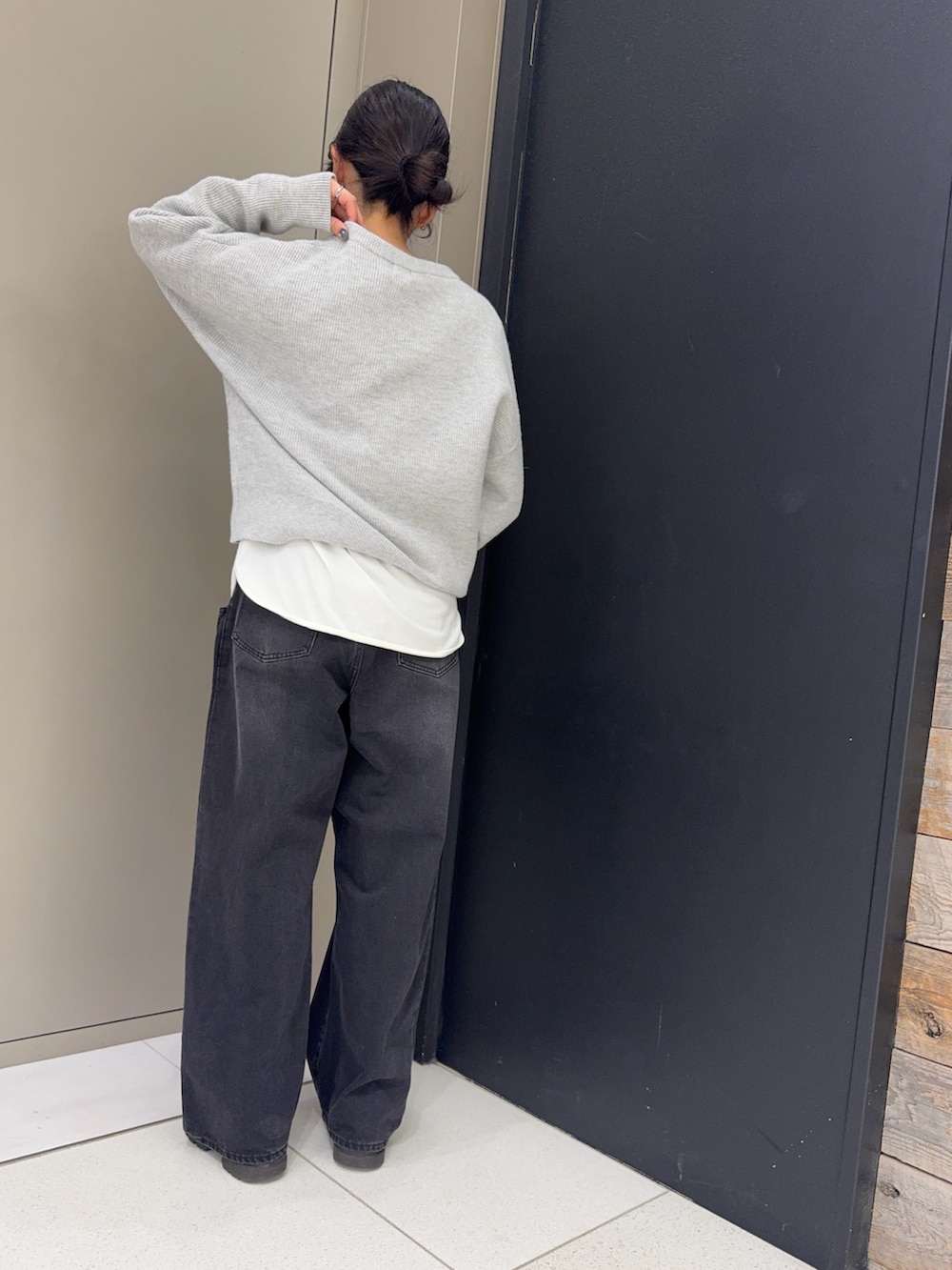 グレー系のニット/セーター、ホワイト系のTシャツ/カットソー、ブラック系のデニムパンツを着用したレディースの冬コーディネートの3枚目の写真