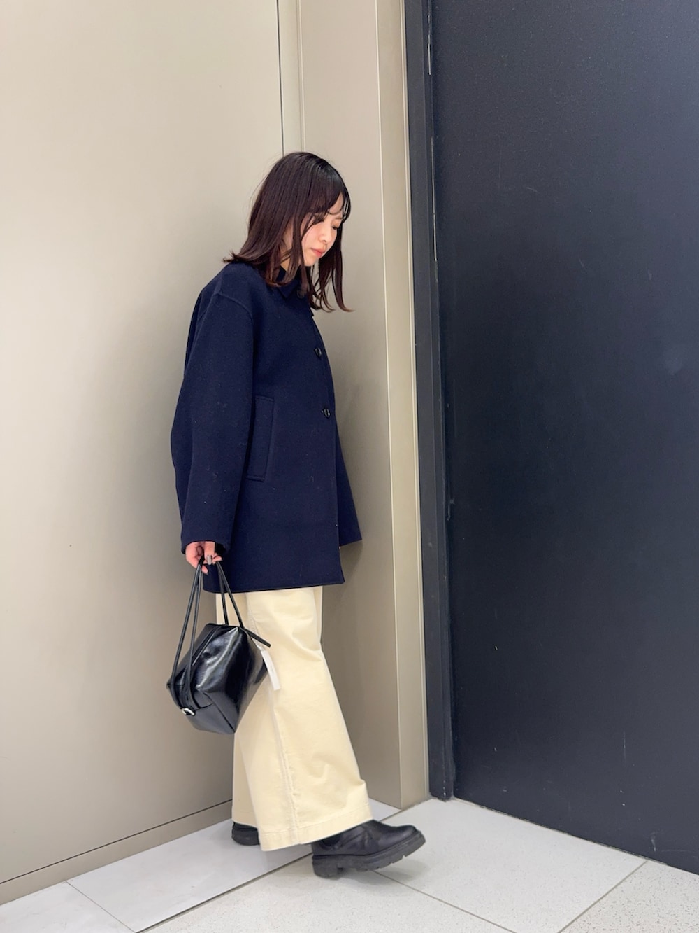 ブルー系のステンカラーコート、ホワイト系のその他パンツ、ブラック系のショルダーバッグを着用したレディースの冬コーディネートの3枚目の写真