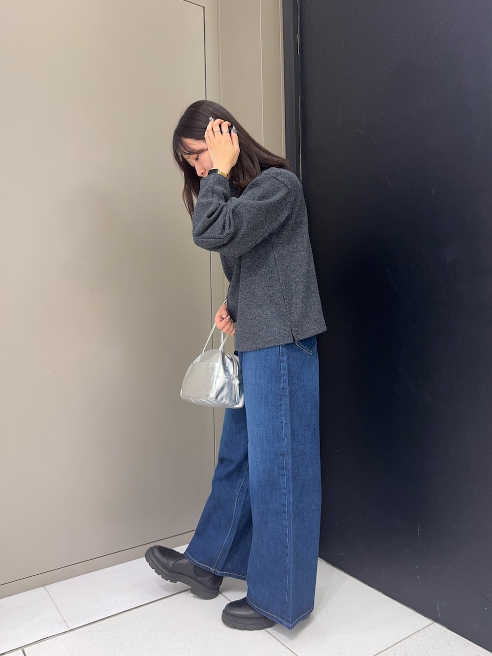 グレー系のTシャツ/カットソー、シルバー系のボストンバッグ、ブルー系のデニムパンツを着用したレディースの冬コーディネートの2枚目の写真