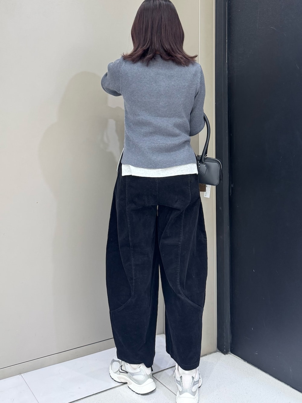 グレー系のニット/セーター、ブラック系のハンドバッグ、ブラック系のその他パンツを着用したレディースの秋コーディネートの4枚目の写真