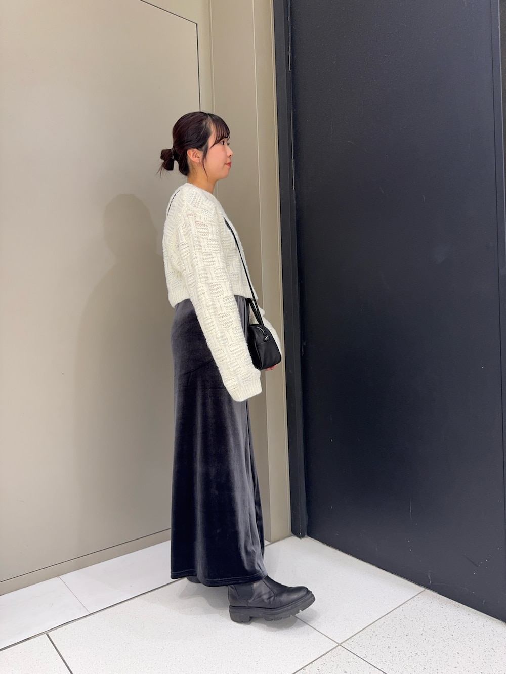 ホワイト系のニット/セーター、グレー系のスカート、ブラック系のハンドバッグを着用したレディースの冬コーディネートの2枚目の写真