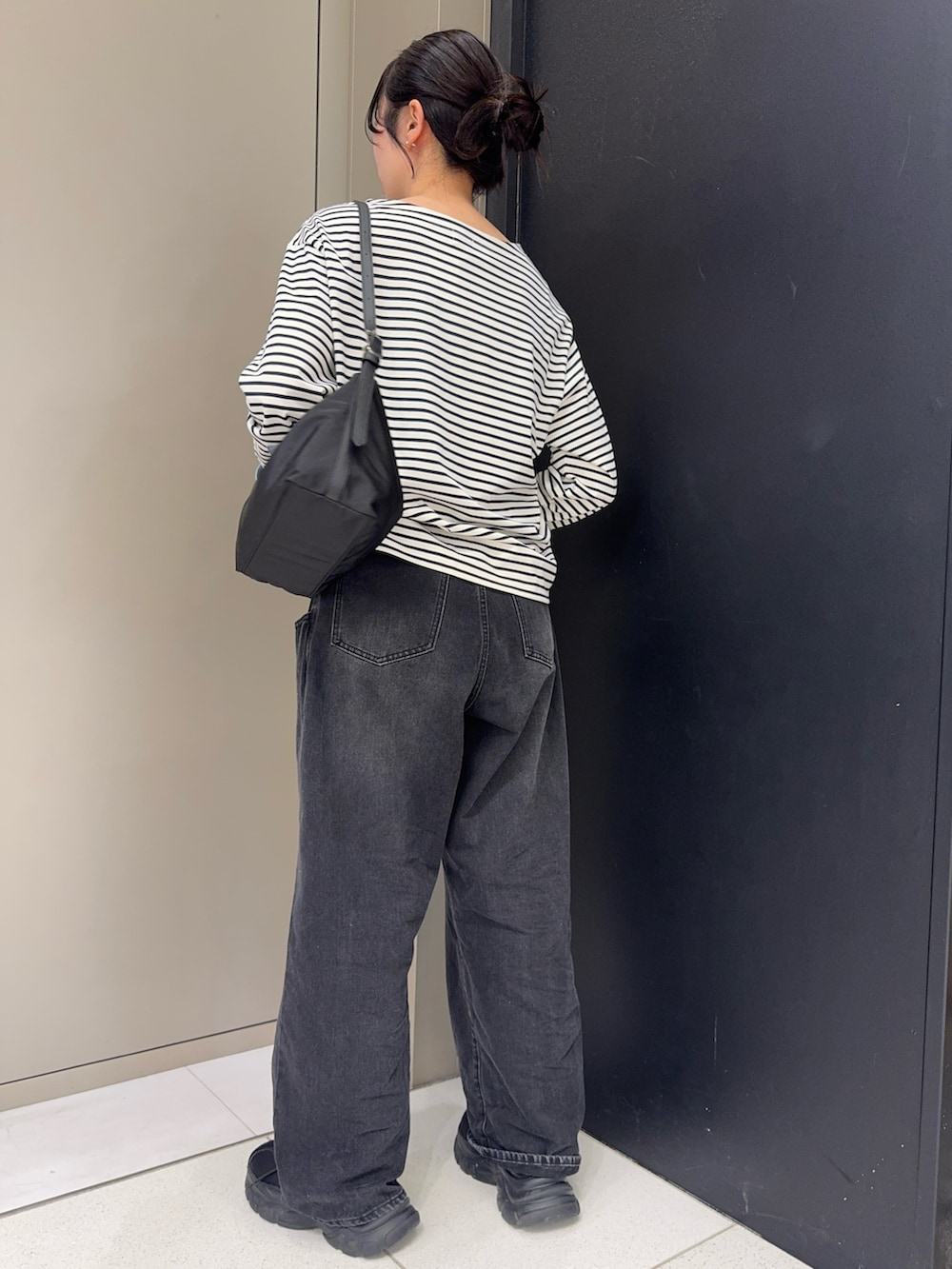 ブラック系のデニムパンツ、ブラック系のショルダーバッグ、ブラック系のスニーカーを着用したレディースの春コーディネートの2枚目の写真