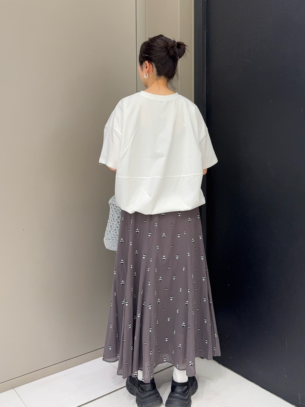 ホワイト系のTシャツ/カットソー、シルバー系のトートバッグ、グレー系のスカートを着用したレディースの春コーディネートの3枚目の写真