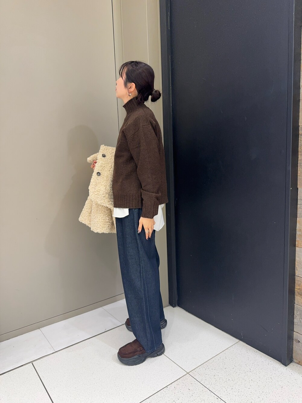 ブラウン系のニット/セーター、ホワイト系のシャツ/ブラウス、ブルー系のデニムパンツを着用したレディースの冬コーディネートの2枚目の写真