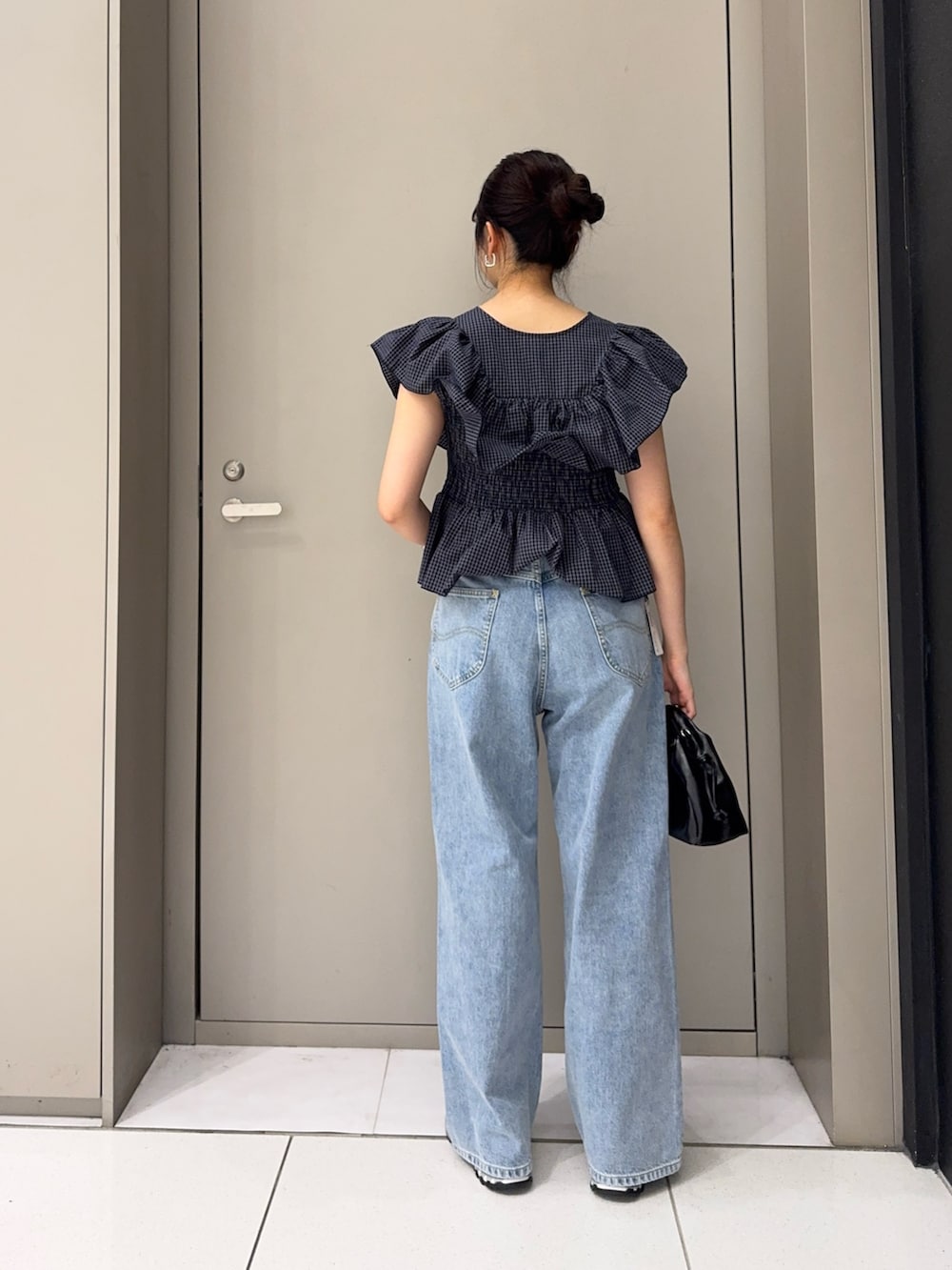 ブルー系のシャツ/ブラウス、ブラック系のハンドバッグ、ブルー系のデニムパンツを着用したレディースの夏コーディネートの2枚目の写真