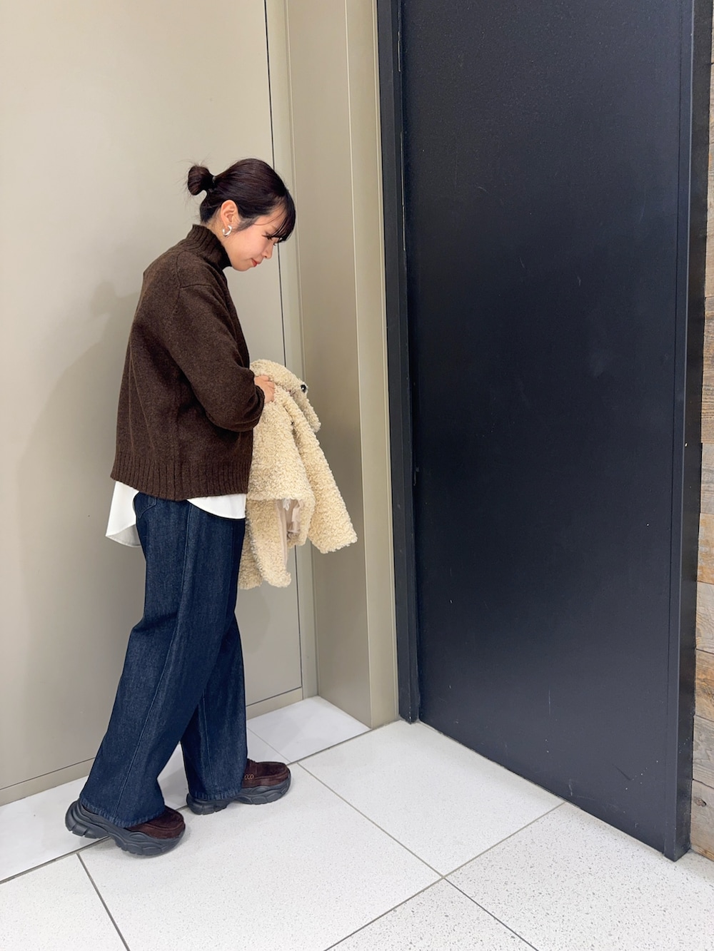 ブラウン系のニット/セーター、ホワイト系のシャツ/ブラウス、ブルー系のデニムパンツを着用したレディースの冬コーディネートの4枚目の写真