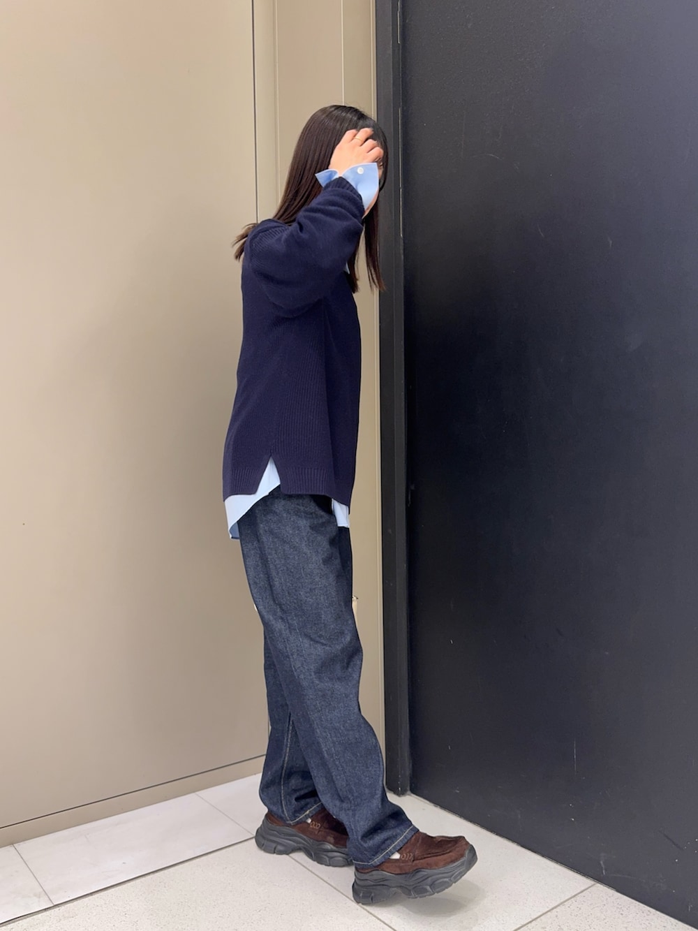 ブルー系のニット/セーター、ブラウン系のローファー、ブルー系のシャツ/ブラウスを着用したレディースの春コーディネートの2枚目の写真