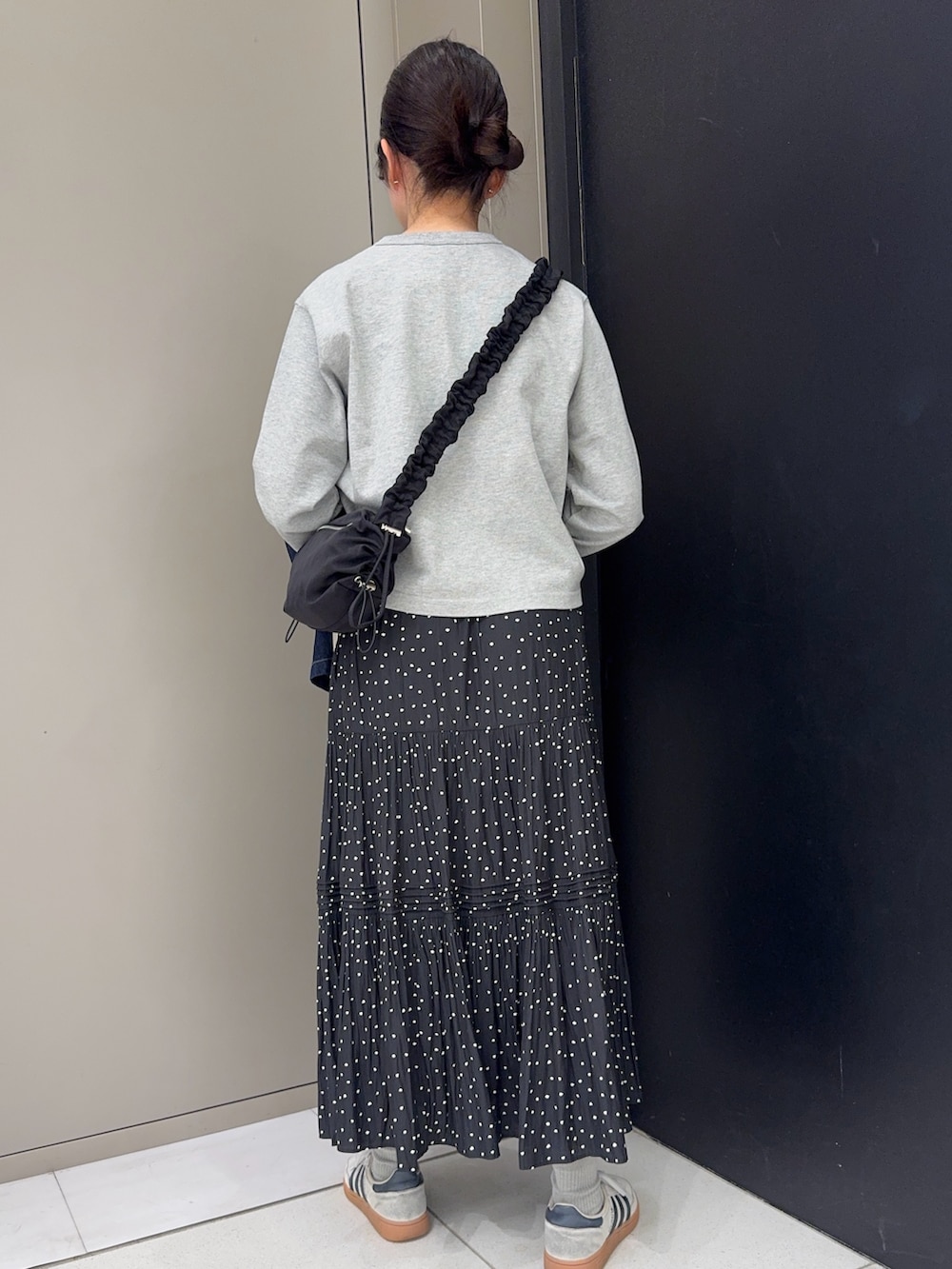 ブルー系のカバーオール、グレー系のカーディガン/ボレロ、ブラック系のスカートを着用したレディースの春コーディネートの5枚目の写真