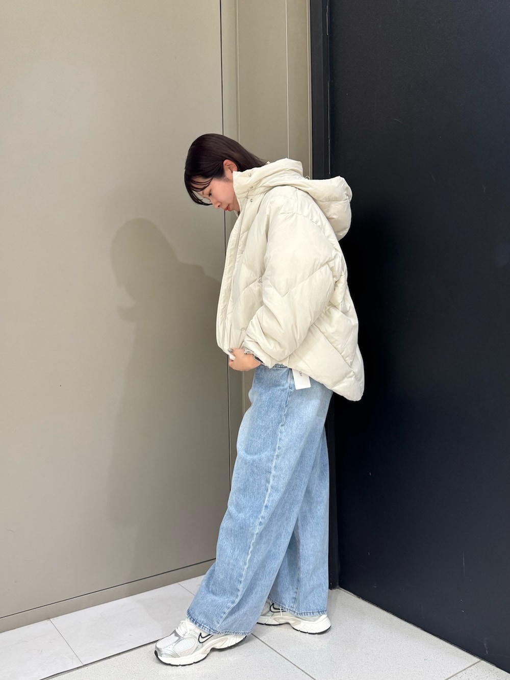 ホワイト系のダウンジャケット/コート、ブルー系のデニムパンツ、ホワイト系のスニーカーを着用したレディースの秋コーディネートの3枚目の写真