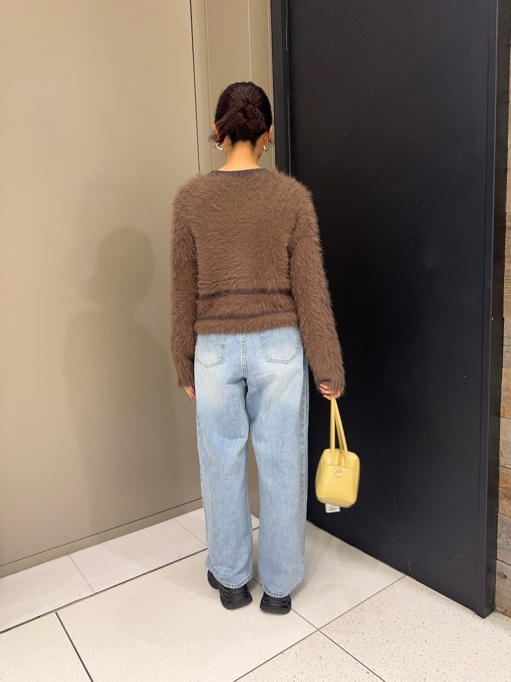 ブラウン系のニット/セーター、ベージュ系のショルダーバッグ、ブルー系のデニムパンツを着用したレディースの冬コーディネートの4枚目の写真