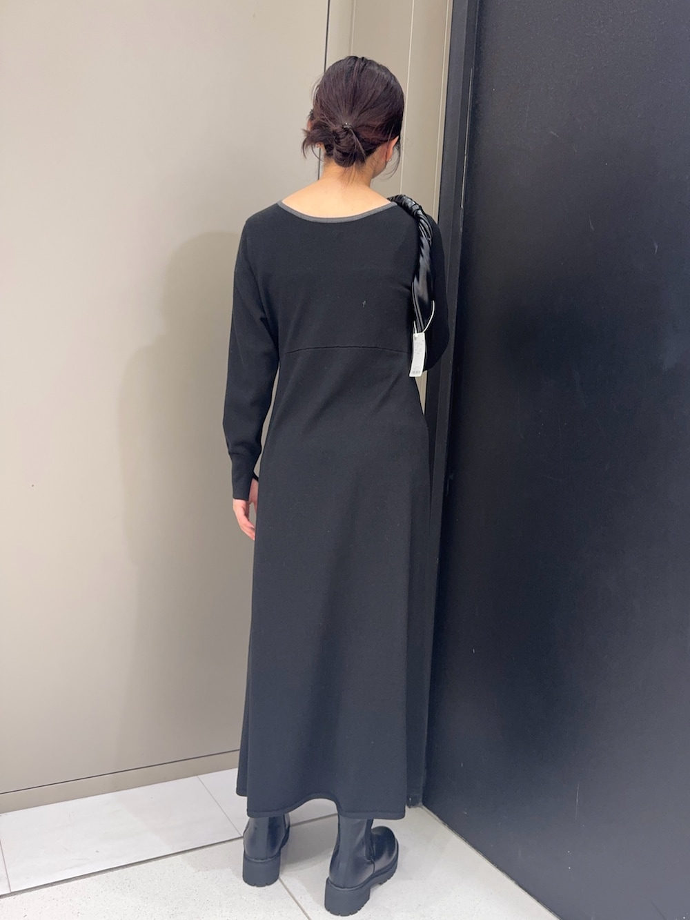 ブラック系のワンピース、ブラック系のブーツ、ブラック系のハンドバッグを着用したレディースの冬コーディネートの3枚目の写真