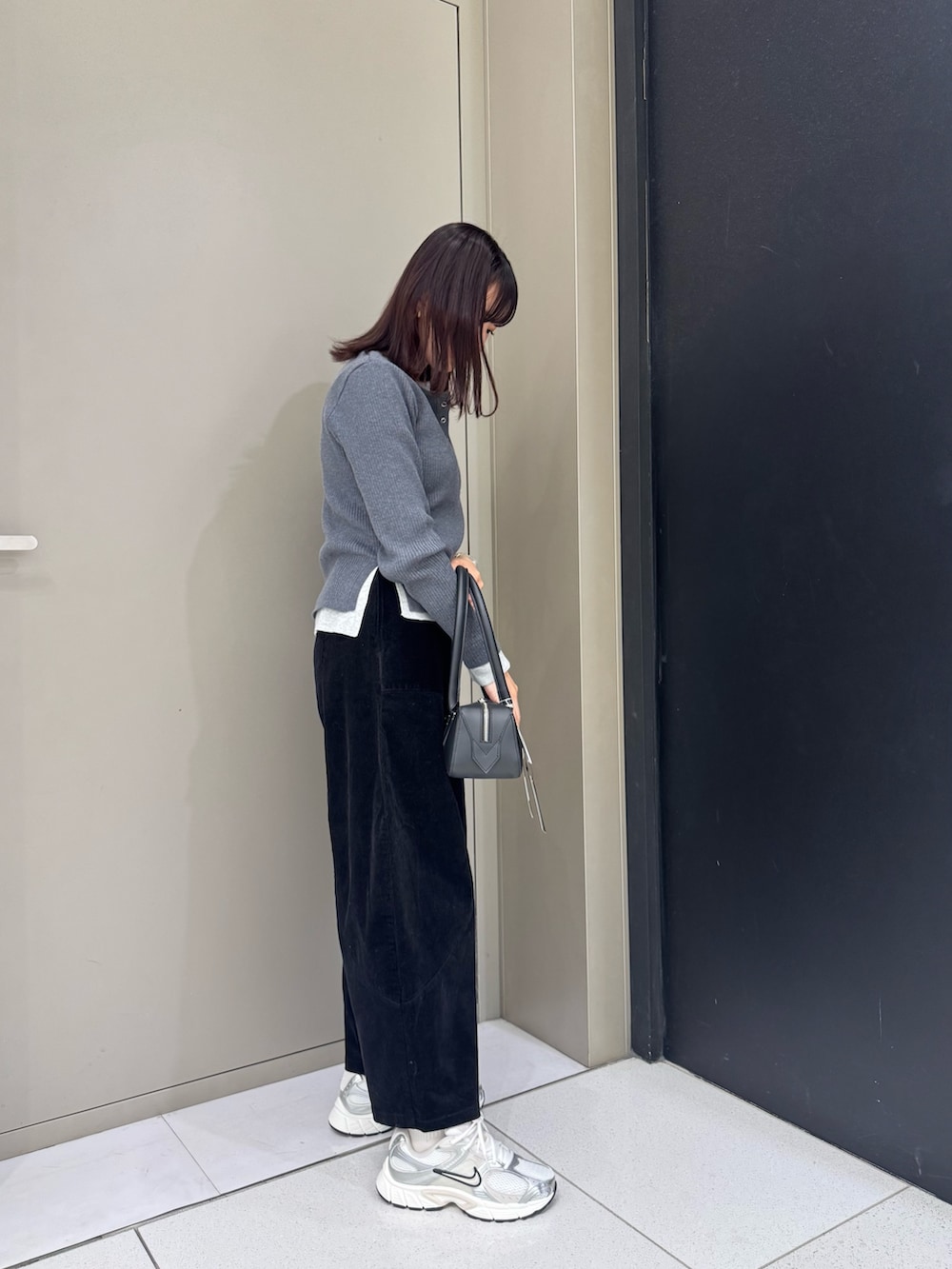 グレー系のニット/セーター、ブラック系のハンドバッグ、ブラック系のその他パンツを着用したレディースの秋コーディネートの2枚目の写真