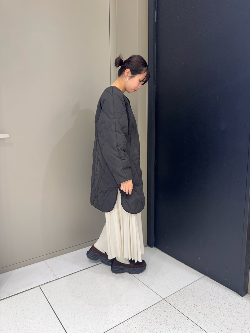 ブラック系のダウンジャケット/コート、グレー系のスカート、ブラウン系のローファーを着用したレディースの冬コーディネートの2枚目の写真