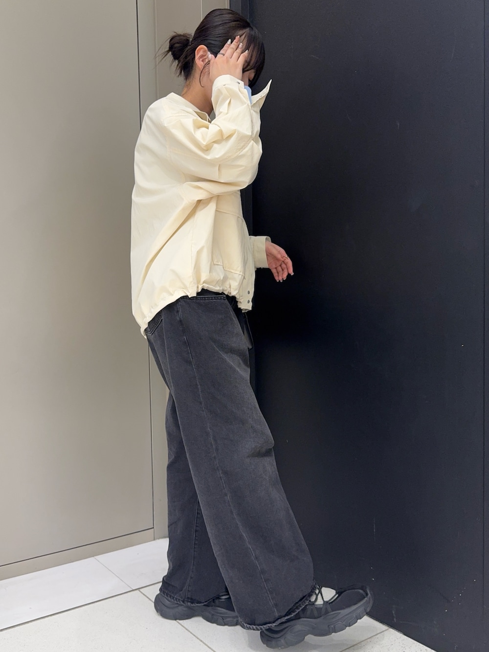 ホワイト系のブルゾン、ブラック系のデニムパンツ、ブラック系のショルダーバッグを着用したレディースの春コーディネートの2枚目の写真