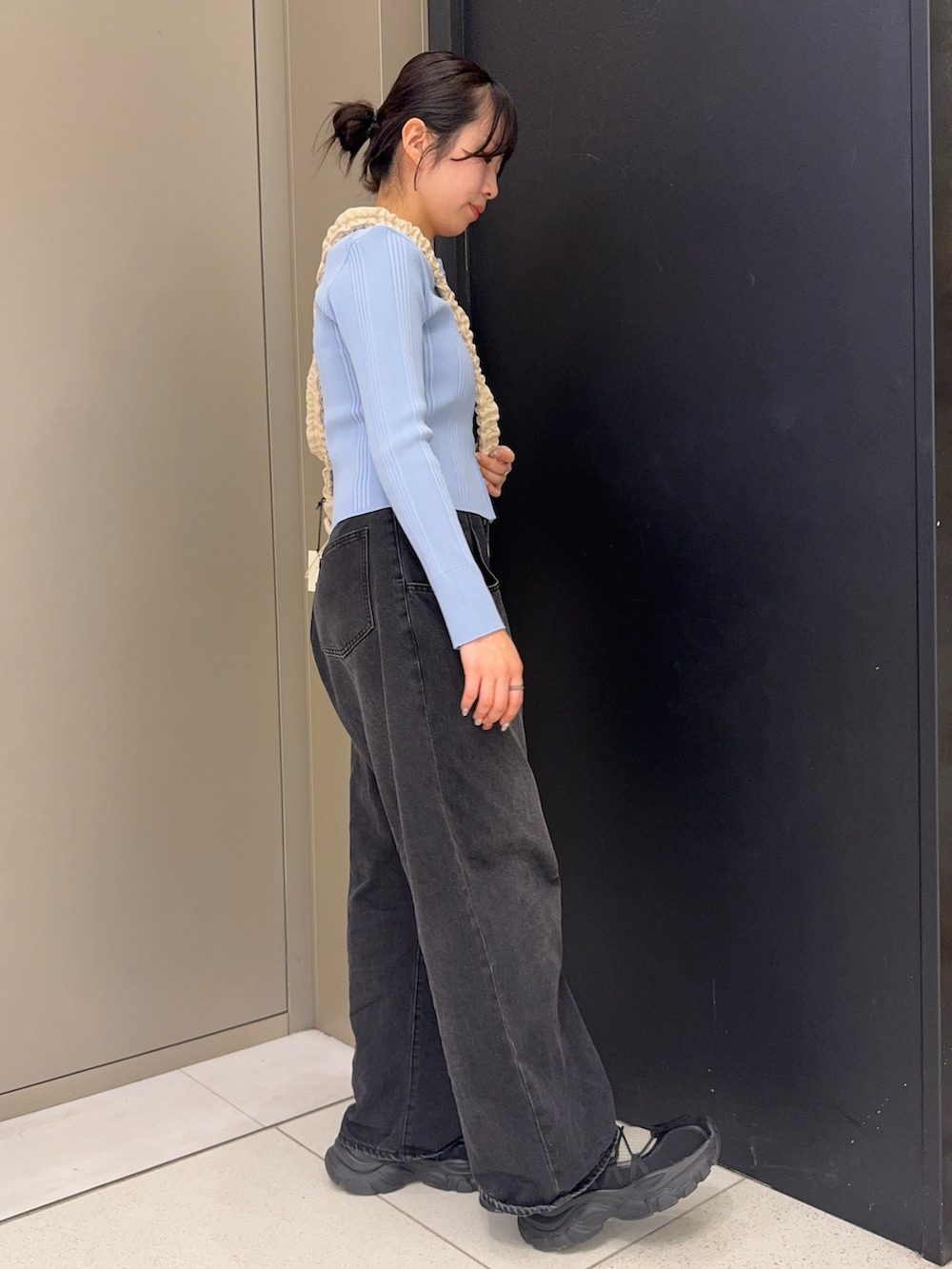 ホワイト系のショルダーバッグ、ブラック系のデニムパンツ、ブラック系のスニーカーを着用したレディースの春コーディネートの2枚目の写真