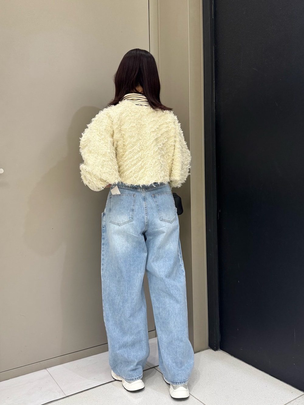 ホワイト系のカーディガン/ボレロ、ブルー系のデニムパンツ、ブラック系のハンドバッグを着用したレディースの秋コーディネートの3枚目の写真