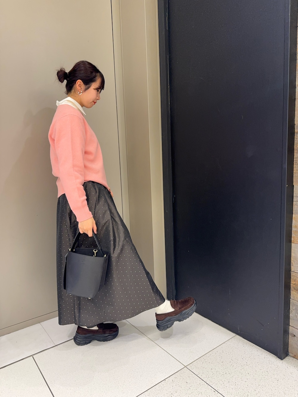 ピンク系のニット/セーター、ブラック系のハンドバッグ、ブラウン系のスカートを着用したレディースの冬コーディネートの2枚目の写真