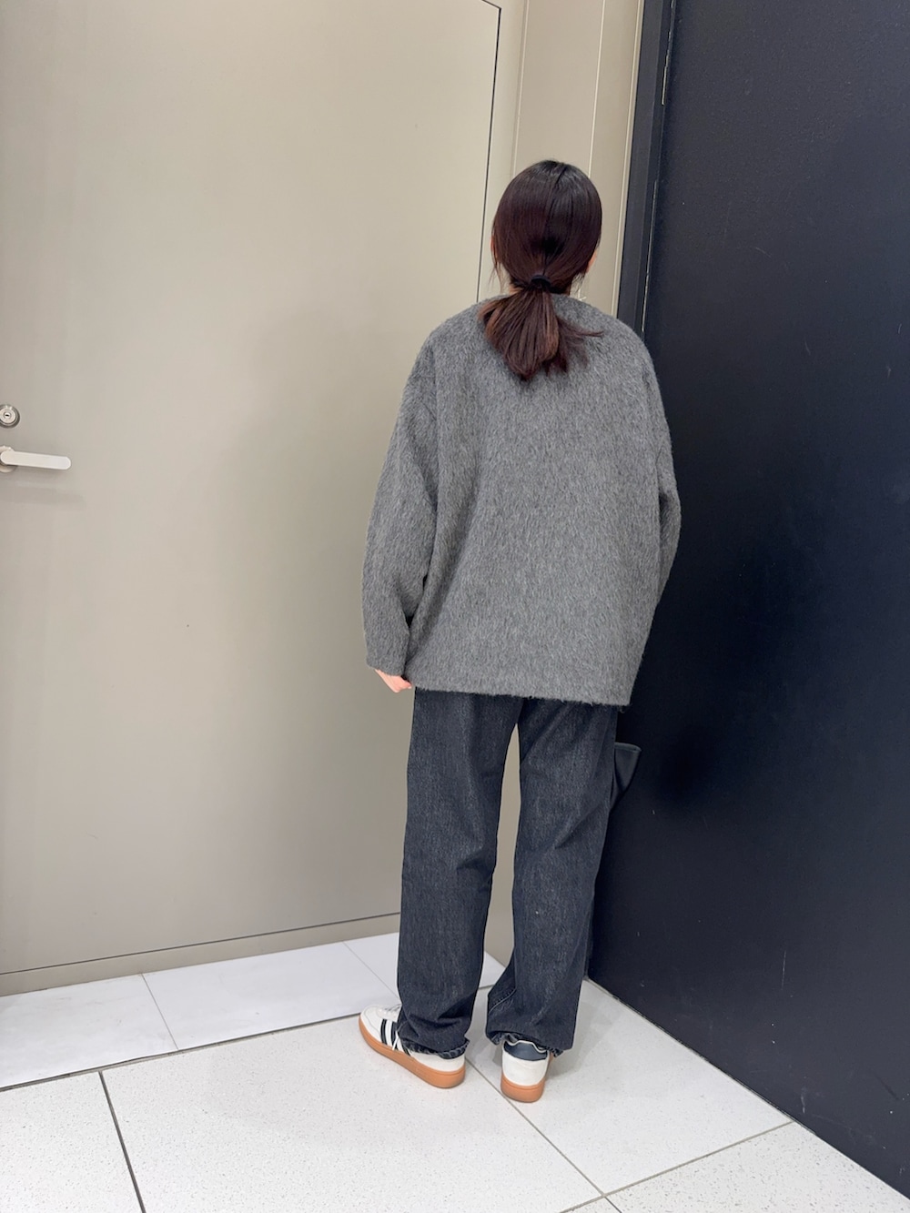 ブラック系のデニムパンツ、ブラック系のハンドバッグ、グレー系のノーカラージャケットを着用したレディースの冬コーディネートの3枚目の写真