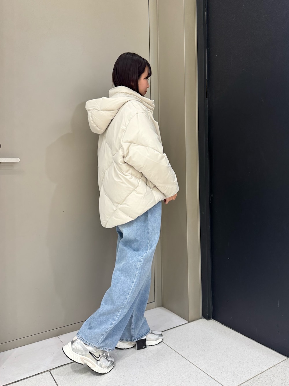 ホワイト系のダウンジャケット/コート、ブルー系のデニムパンツ、ホワイト系のスニーカーを着用したレディースの秋コーディネートの4枚目の写真