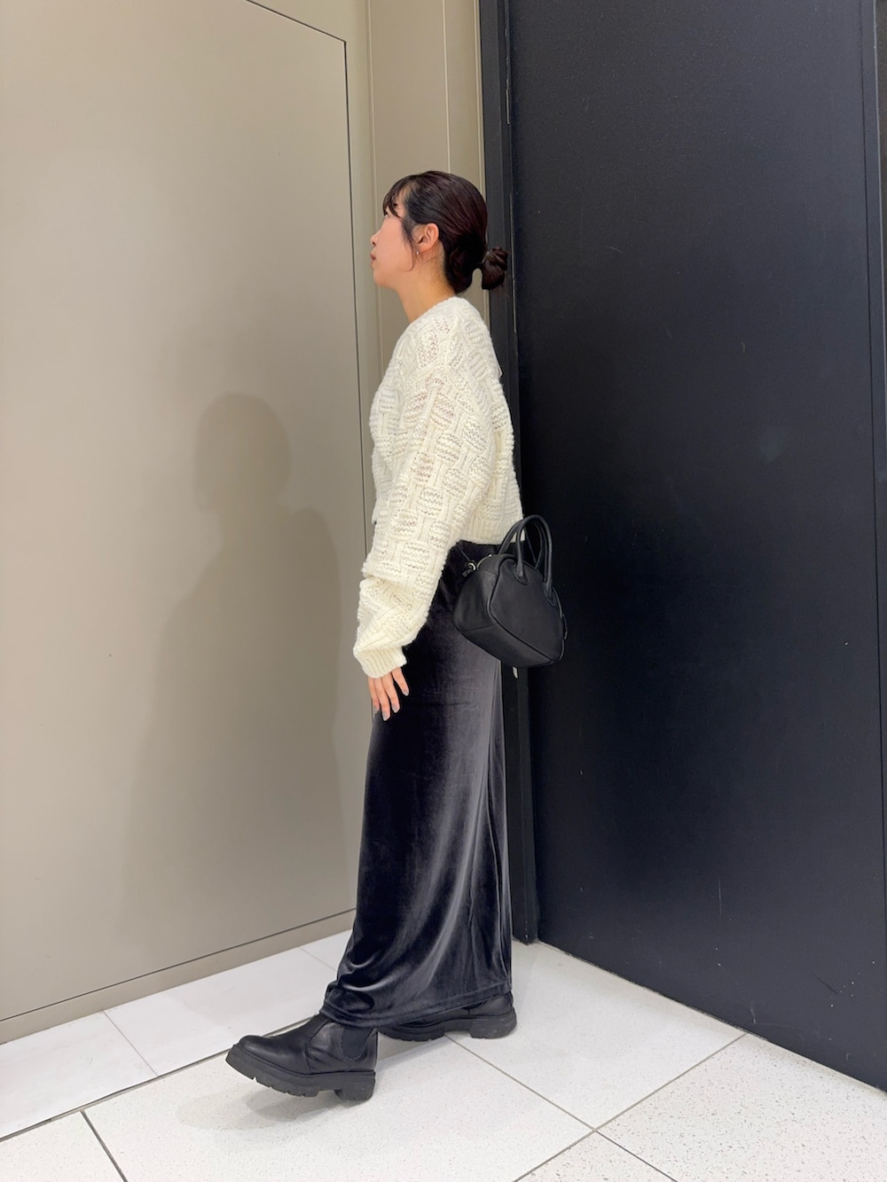 ホワイト系のニット/セーター、グレー系のスカート、ブラック系のハンドバッグを着用したレディースの冬コーディネートの3枚目の写真