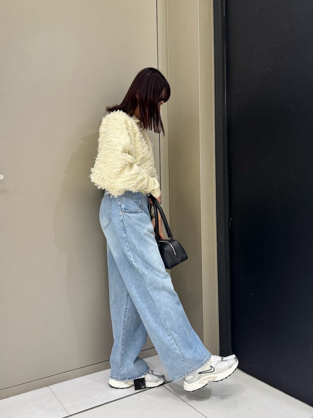 ホワイト系のカーディガン/ボレロ、ブルー系のデニムパンツ、ブラック系のハンドバッグを着用したレディースの秋コーディネートの2枚目の写真