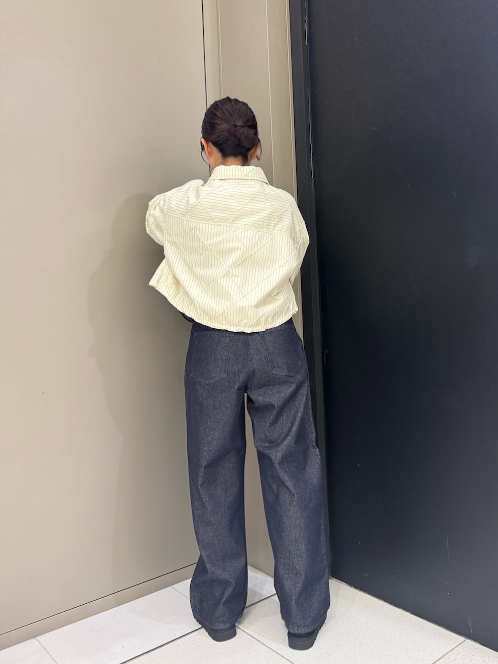 ホワイト系のダウンジャケット/コート、ブラック系のハンドバッグ、ブルー系のデニムパンツを着用したレディースの秋コーディネートの4枚目の写真