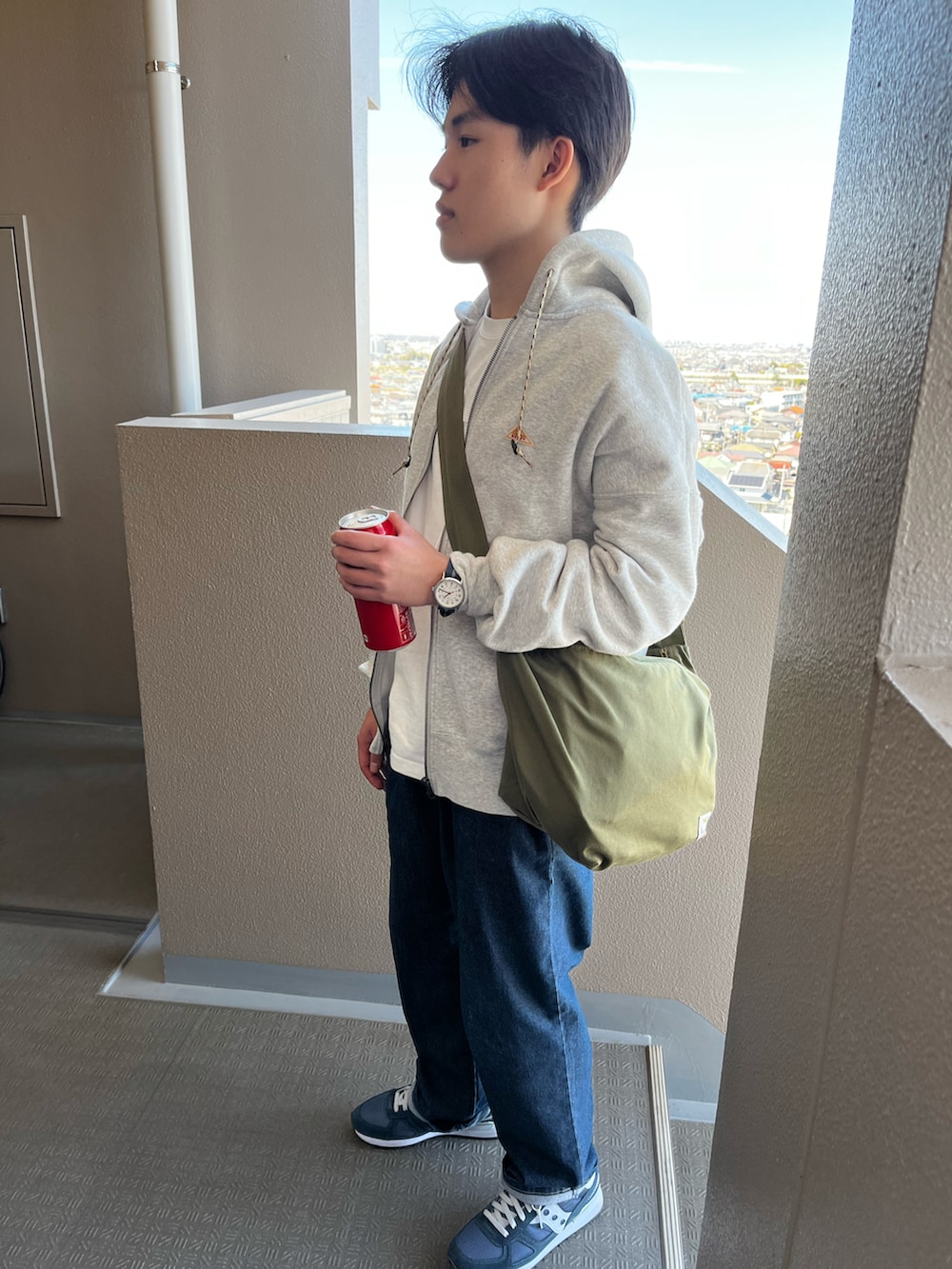 グレー系のパーカー、ブルー系のデニムパンツ、ブルー系のスニーカーを着用したキッズの春コーディネートの3枚目の写真