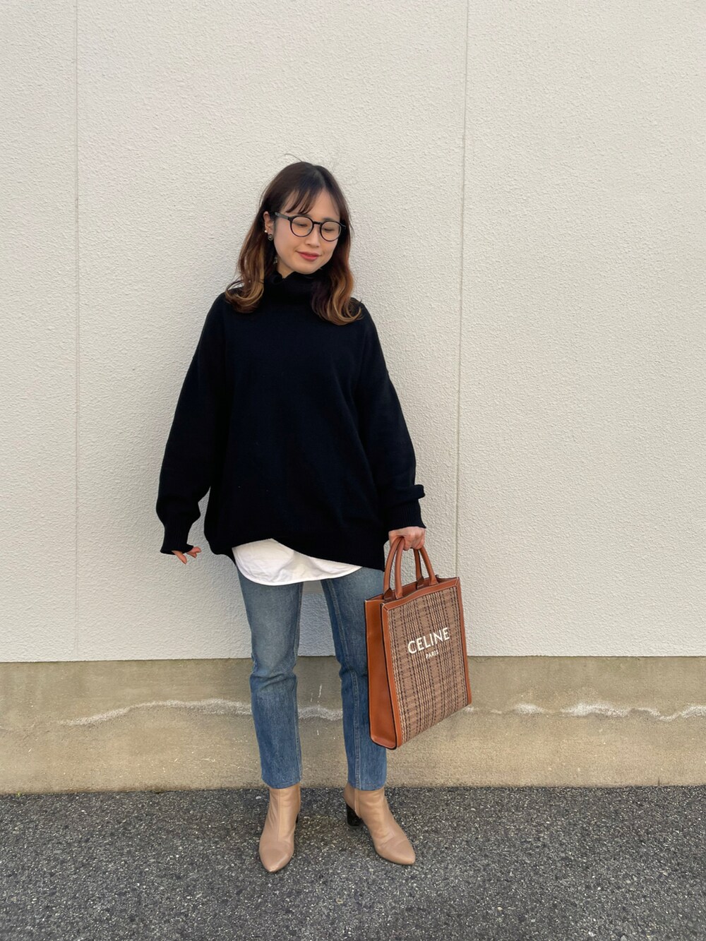 ブラック系のニット/セーター、ブルー系のデニムパンツ、ベージュ系のブーツを着用したレディースの冬コーディネートの2枚目の写真