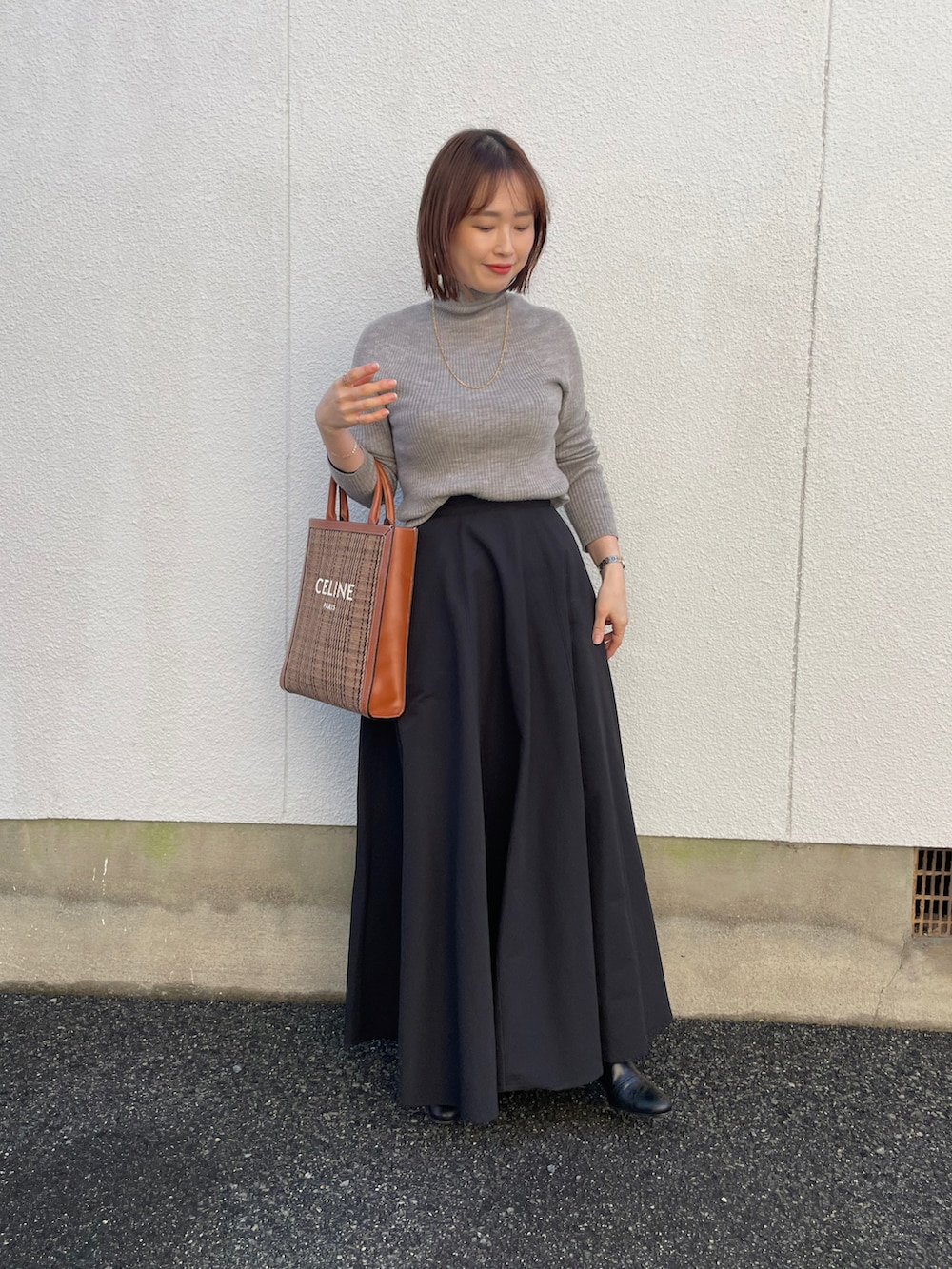 ブラック系のスカート、ブラック系のニット/セーター、ブラック系のブーツを着用したレディースの冬コーディネートの2枚目の写真