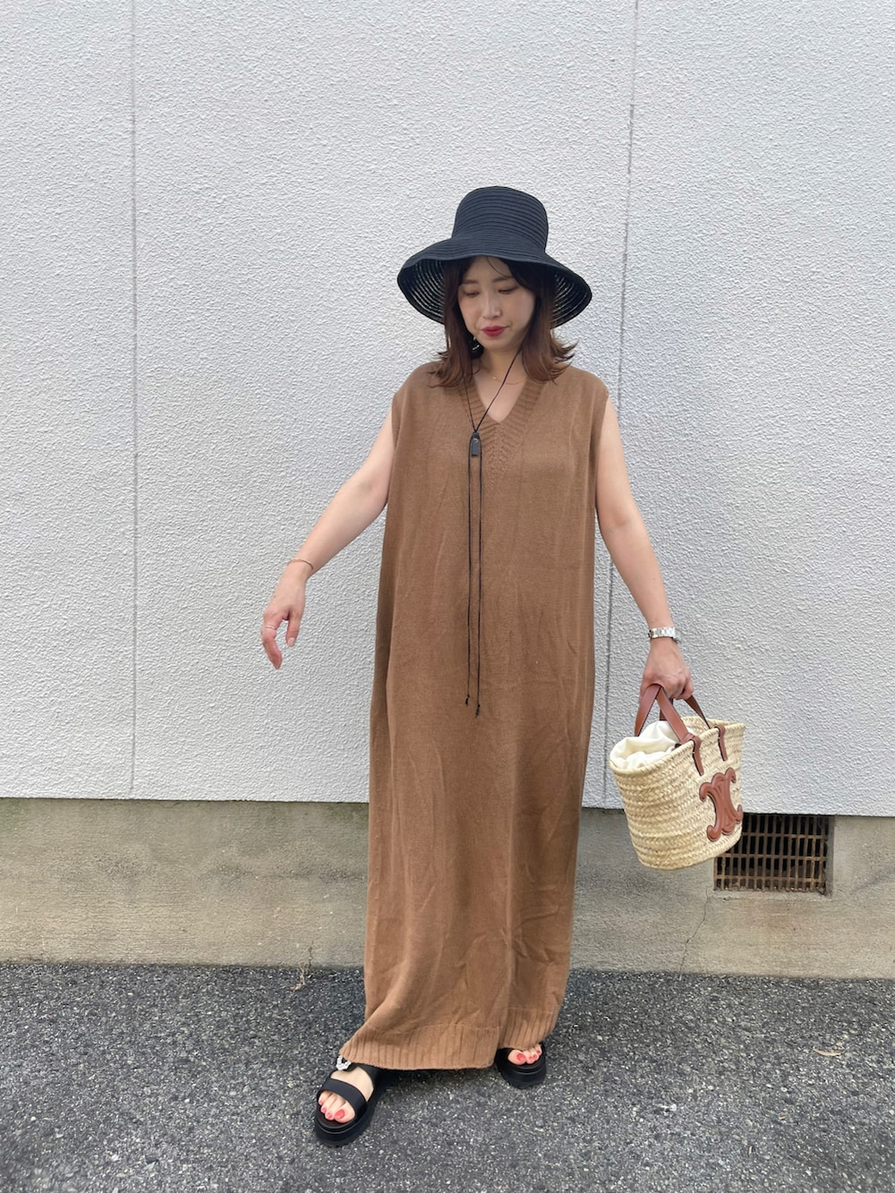 イエロー系のワンピース、ブラック系のサンダル、ブラック系のハットを着用したレディースの夏コーディネートの2枚目の写真