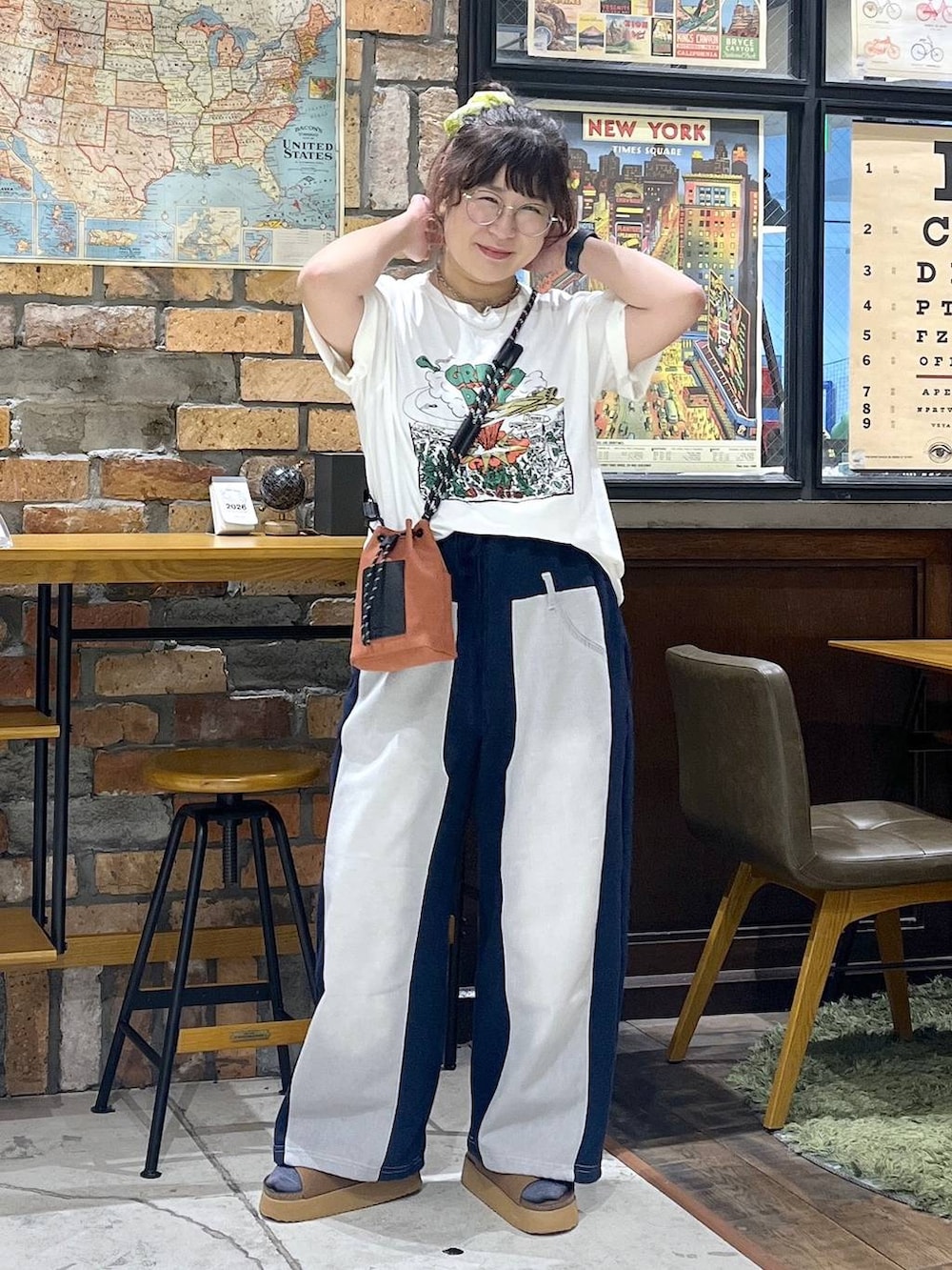 オレンジ系のショルダーバッグ、ブルー系のデニムパンツ、ブラウン系のサンダルを着用したレディースの夏コーディネートの3枚目の写真