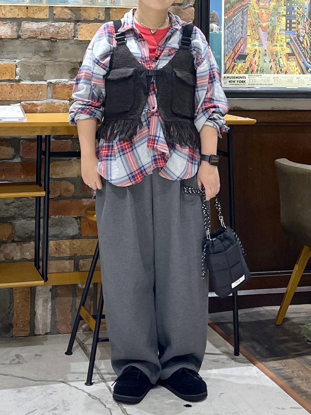 ブラウン系のベスト、レッド系のTシャツ/カットソー、ブラック系のモカシン/デッキシューズを着用したレディースの秋コーディネートの2枚目の写真