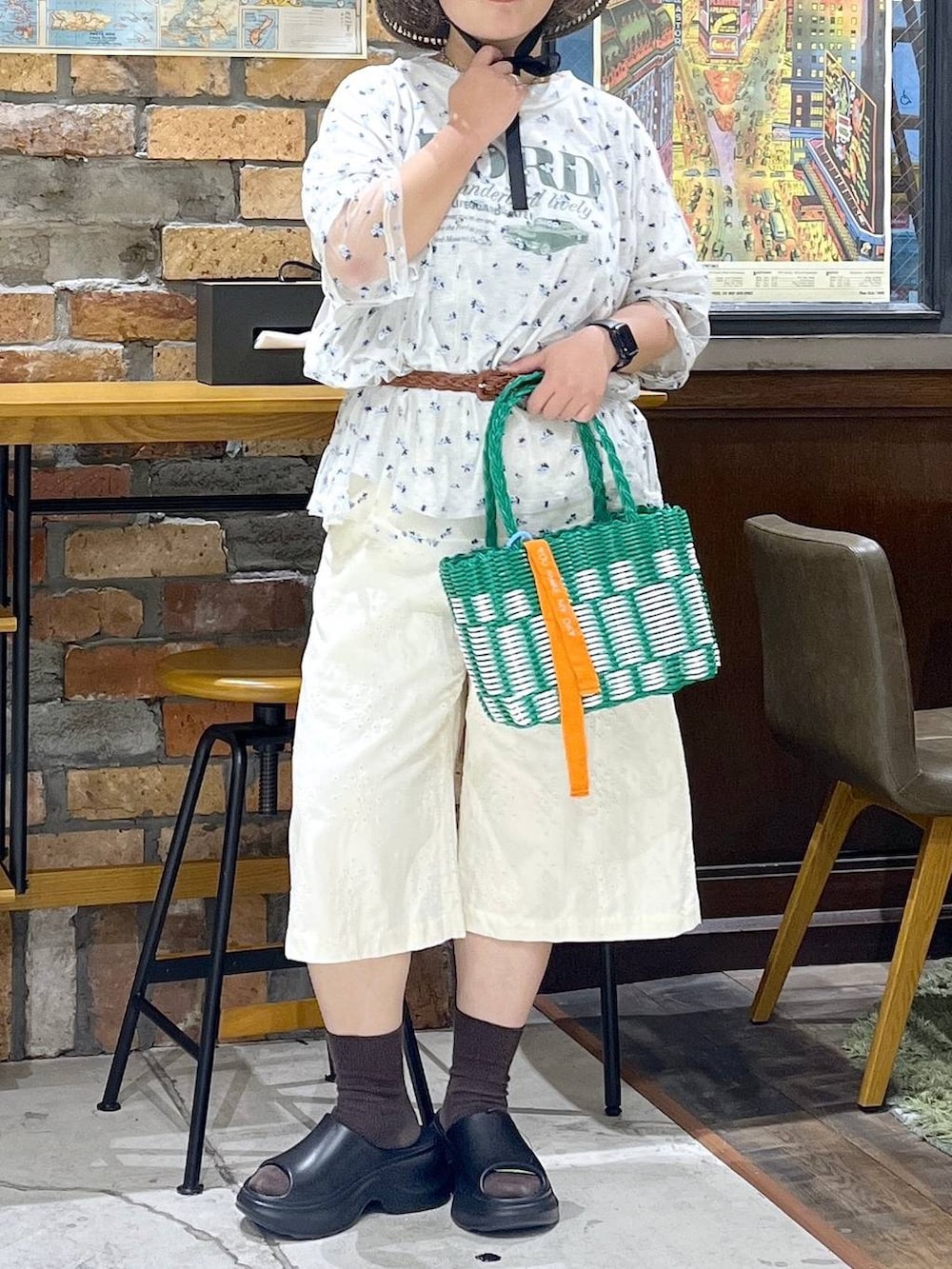ブラック系のサンダル、ベージュ系のTシャツ/カットソー、グリーン系のかごバッグを着用したレディースの夏コーディネートの2枚目の写真