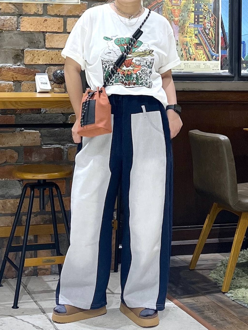 オレンジ系のショルダーバッグ、ブルー系のデニムパンツ、ブラウン系のサンダルを着用したレディースの夏コーディネートの2枚目の写真