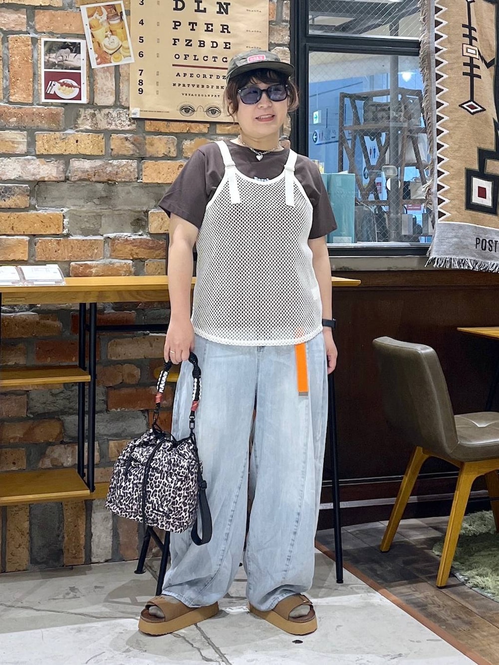ホワイト系のタンクトップ、ブラウン系のTシャツ/カットソー、ブルー系のデニムパンツを着用したレディースの夏コーディネートの3枚目の写真