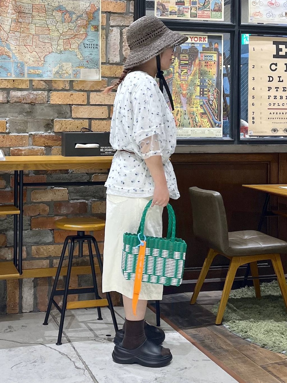 ブラック系のサンダル、ベージュ系のTシャツ/カットソー、グリーン系のかごバッグを着用したレディースの夏コーディネートの6枚目の写真