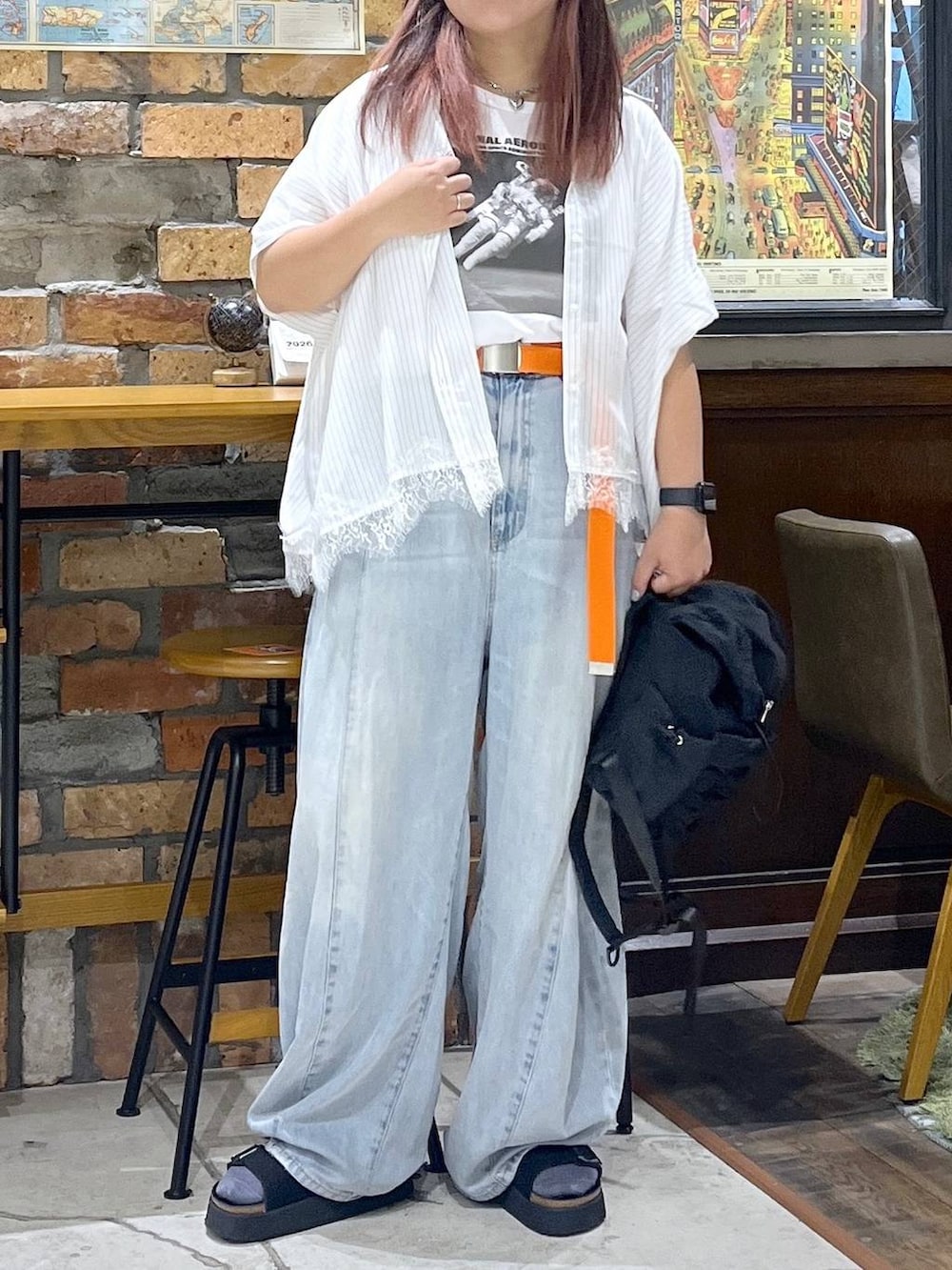ブルー系のデニムパンツ、ブラック系のサンダル、ブラック系のバックパック/リュックを着用したレディースの夏コーディネートの2枚目の写真