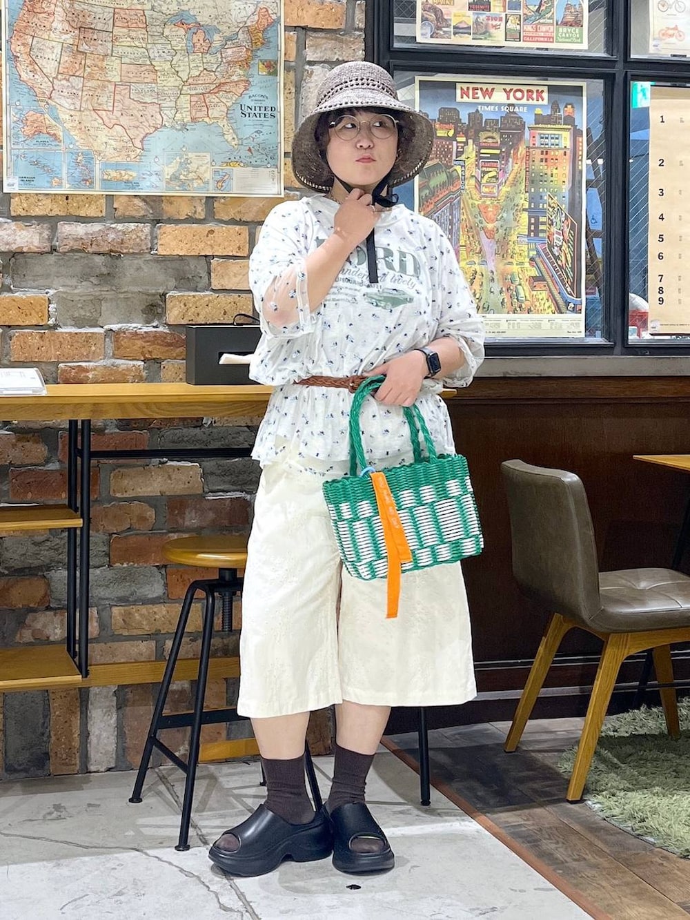 ブラック系のサンダル、ベージュ系のTシャツ/カットソー、グリーン系のかごバッグを着用したレディースの夏コーディネートの3枚目の写真