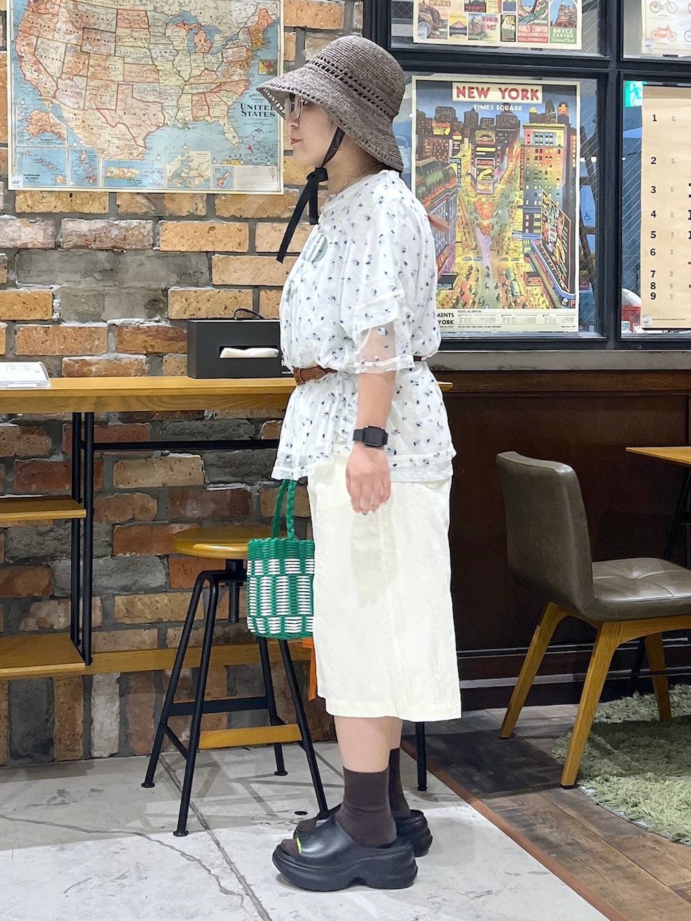 ブラック系のサンダル、ベージュ系のTシャツ/カットソー、グリーン系のかごバッグを着用したレディースの夏コーディネートの4枚目の写真