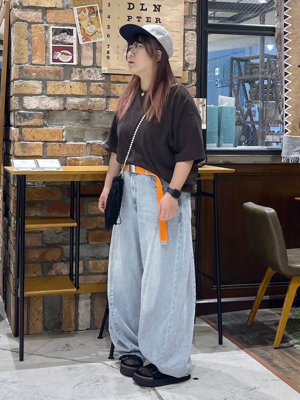 ブルー系のデニムパンツ、ブラウン系のTシャツ/カットソー、ブラック系のサンダルを着用したレディースの夏コーディネートの4枚目の写真