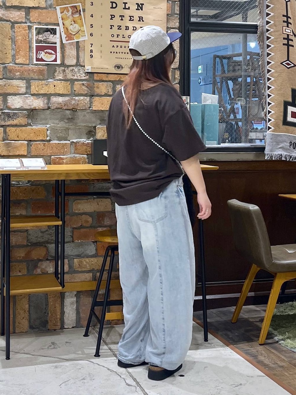 ブルー系のデニムパンツ、ブラウン系のTシャツ/カットソー、ブラック系のサンダルを着用したレディースの夏コーディネートの6枚目の写真
