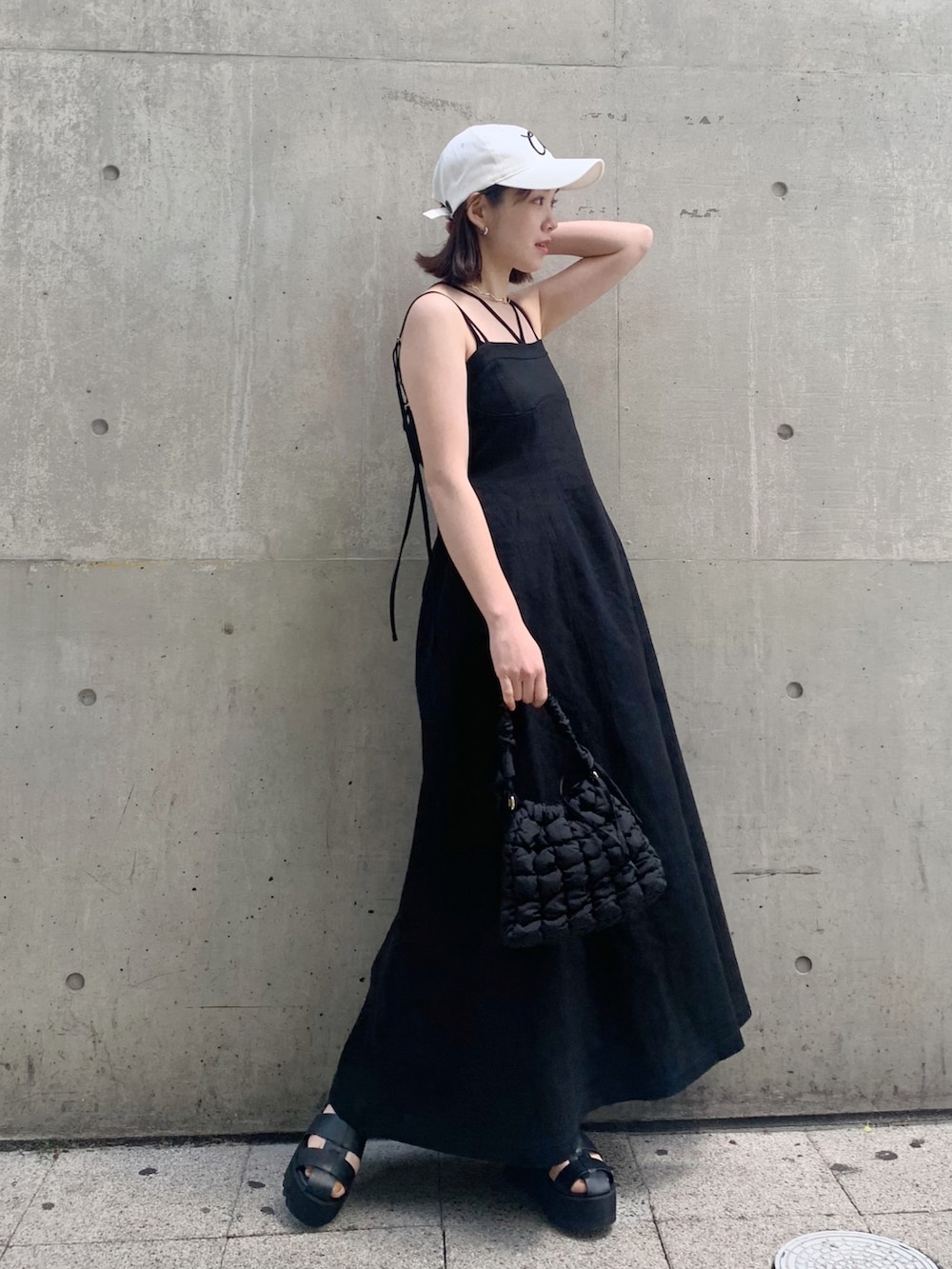 ブラック系のワンピース、ブラック系のショルダーバッグ、ブラック系のサンダルを着用したレディースの春コーディネートの2枚目の写真