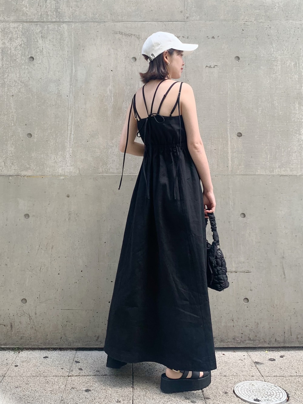 ブラック系のワンピース、ブラック系のショルダーバッグ、ブラック系のサンダルを着用したレディースの春コーディネートの3枚目の写真