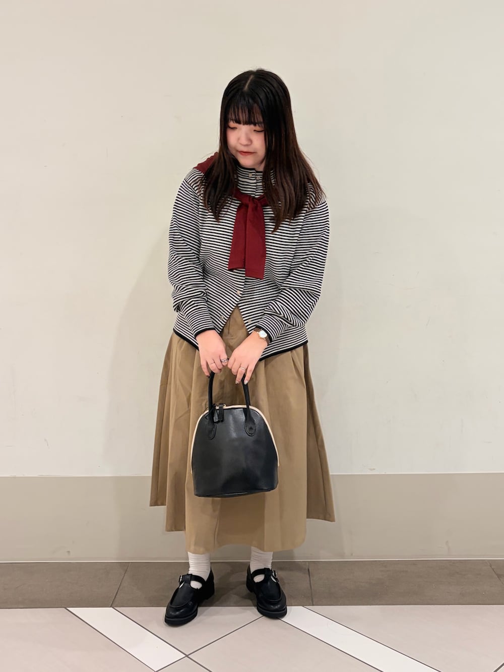 ブラック系のローファー、ホワイト系のカーディガン/ボレロ、ベージュ系のスカートを着用したレディースの秋コーディネートの3枚目の写真